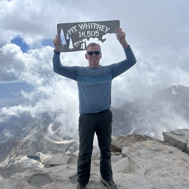 Dale Ferrario holding the summit sign on Mt. Whitney, 14,505 feet